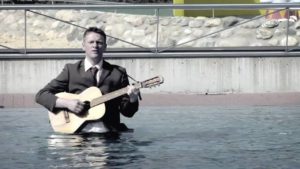 Dirk Schelpmeier mit Guitarre in einem See