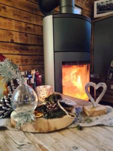Foto vom winterlichen Tischschmuck und dem brennenden Kamin im Hintergrund